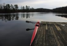 Getting back to the basics at Calm Waters Rowing A photo of a single rowing shell on still water, in the morning, alongside the dock at the training launch for Calm Waters Rowing.