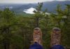 Practical gifts for the active traveler Hiking boots in the foreground and a treeline in the background, as if the photo was taken on the edge of a cliff.