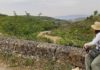 Camino de Santiago: Walking the French Way princess-style Woman sits on a stone fence and looks over a sprawling valley in Northern Spain, during her walk on the Camino de Santiago.