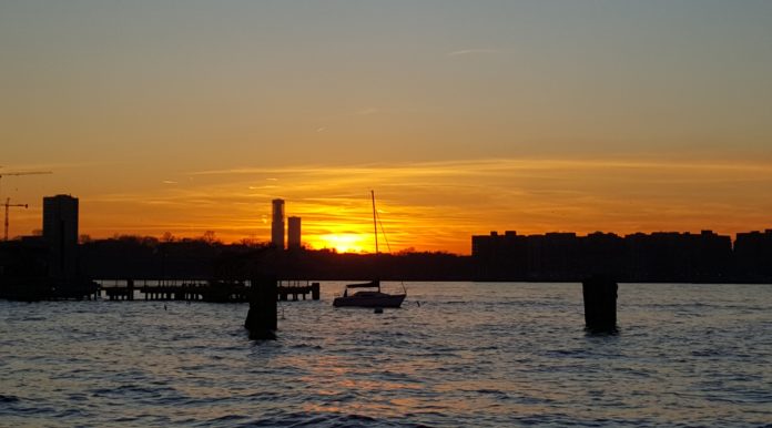 Photo of a beautiful sunset along the Hudson River, with silhouette of moored sail boat. Taken while walking around Manhattan.