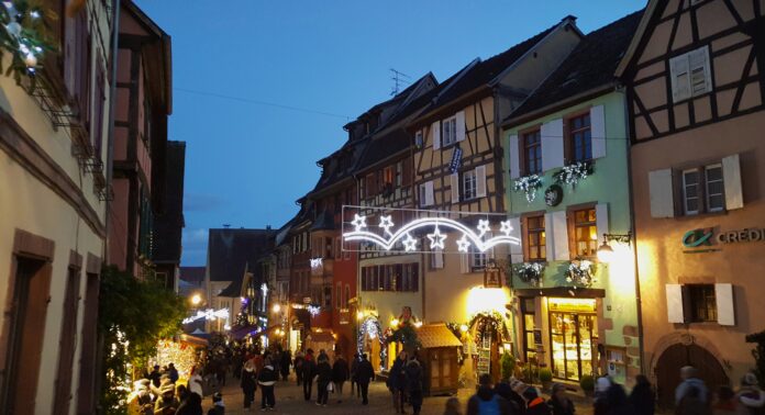 A charming historic European town at dusk, lit up all aglow with Christmas lights, shops, and shoppers.