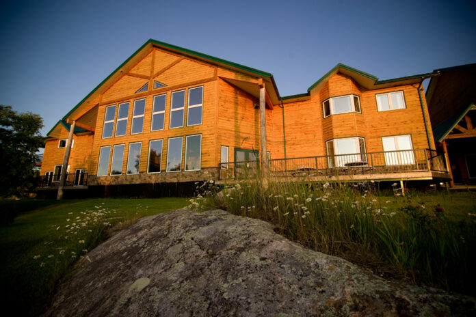 A picture of a massive wooden lodge building, which is part of a wilderness resort designed for corporate retreats.