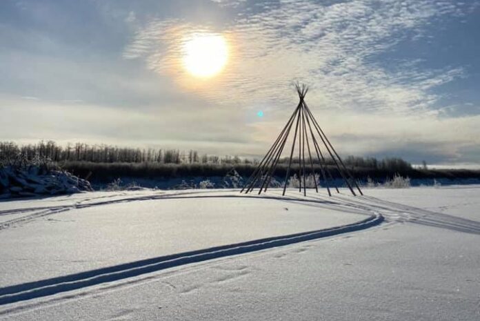 Sun shines bright and low in the sky over a winter wilderness landscape.