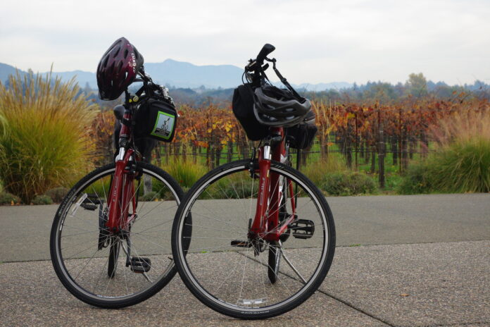 Two road bikes with helmets on the handlebars are parked side by side on a country road, with a sprawling field in the back. Riders pursuing fitness goals.