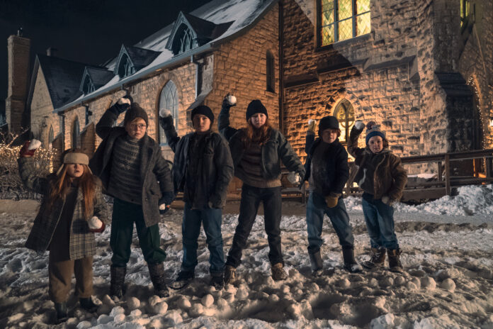 Six kids who are siblings stand in line, in front of a church at night, in winter, with arms raised, holding snowballs and ready to fire, in the movie The Best Christmas Pageant Ever.