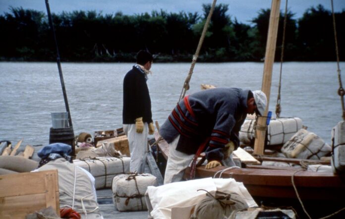 Two adventurers dressed as 1840's yorkmen inspect the gear that is packed inside their york boat.