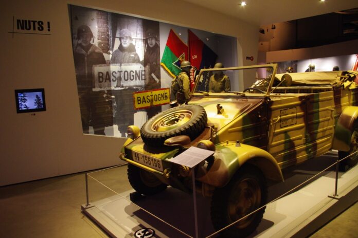 A Second World War exhibit featuring a tank, uniforms, and old photos, at the Bastogne War Museum in Belgium.