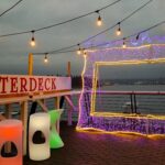 Vancouver at Christmas: Winterless wonderland on the west coast A picture frame made from purple LED lights is on a deck, with the sign 'winterdeck' beside it, and an ocean view behind it.